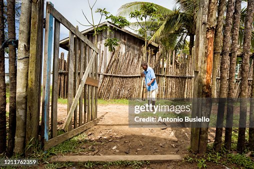 Hombre entrando a su vivienda de madera por el portón